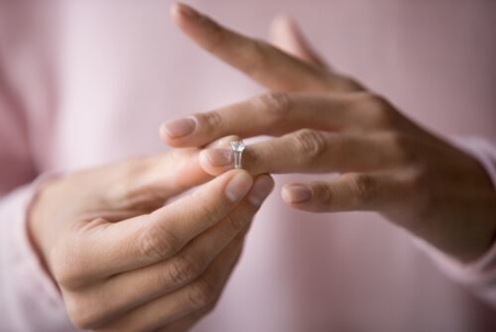 woman wearing pink taking off her wedding ring