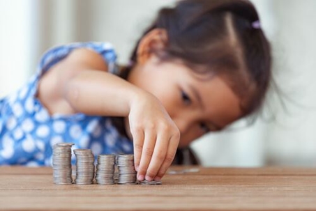 little girl in blue dress counting coins