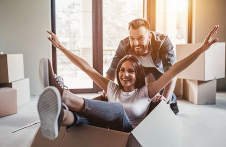 man pushing woman sitting in moving box and pretending to be a plane