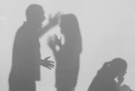 silhouette of couple arguing with sad child in background
